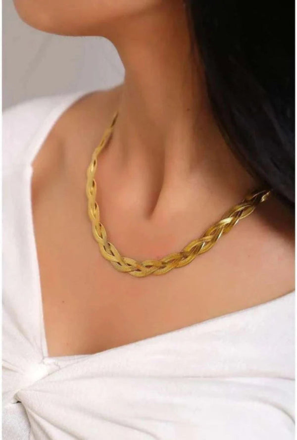 Gold necklace worn by a person against a neutral background