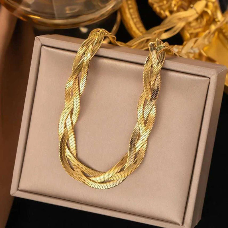 Gold braided necklace on a beige jewelry box with a blurred background